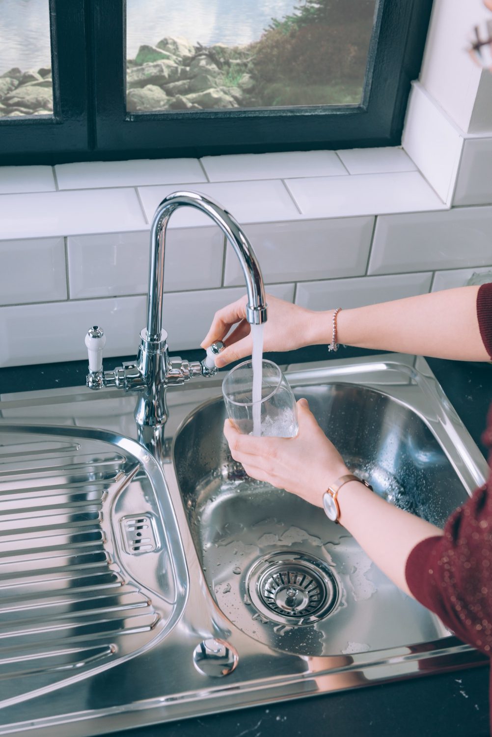 woman-filling-glass-with-water-from-steel-faucet-kitchen